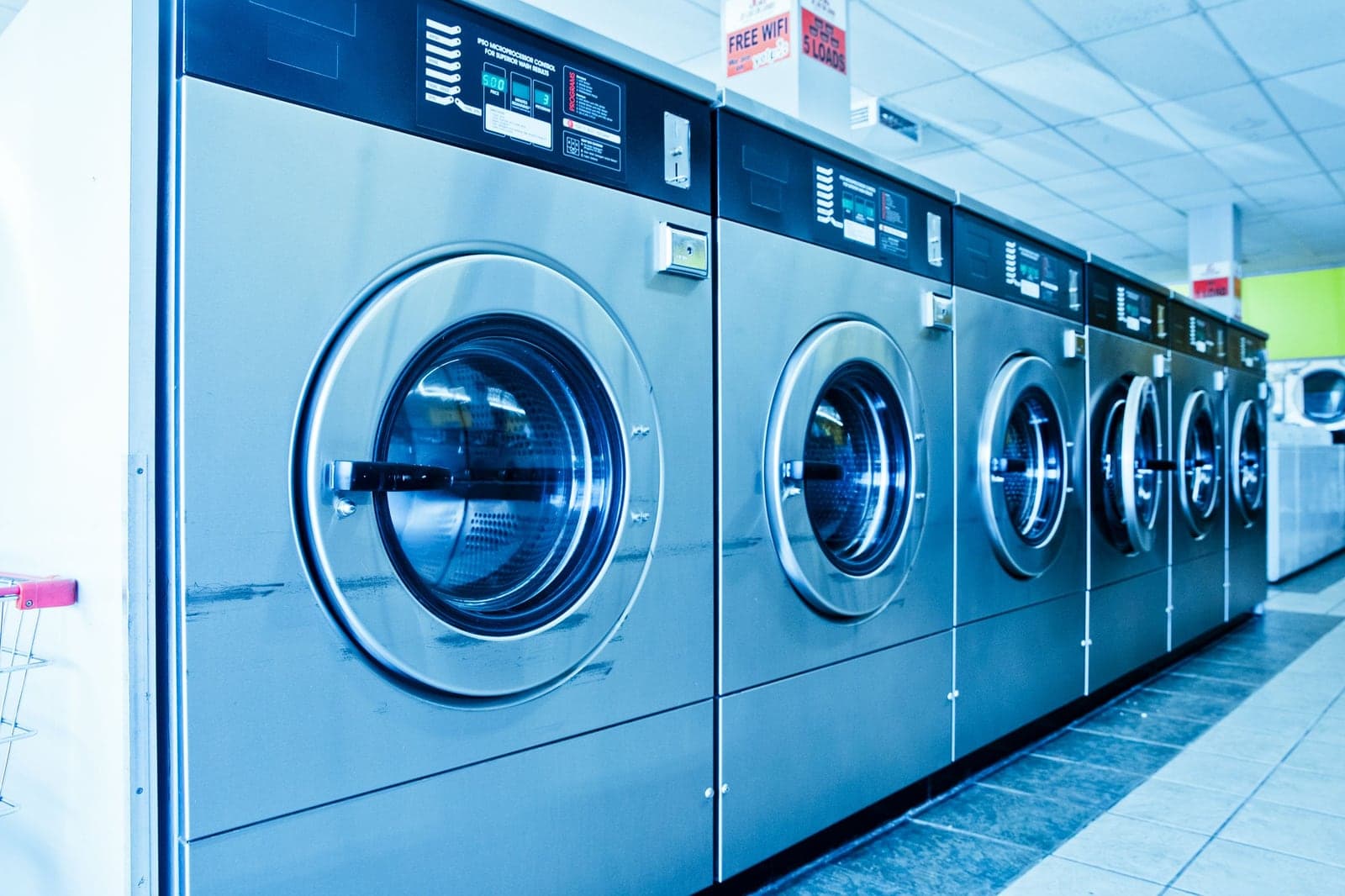 Row of stainless steel front-loading machines in a laundromat
