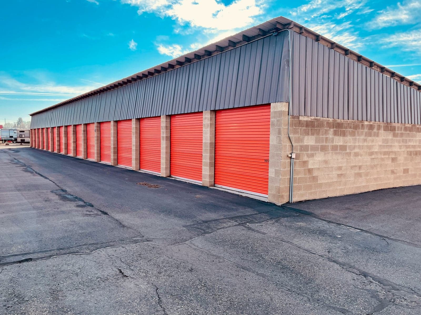 Row of red roll-up doors at a drive-up self-storage facility